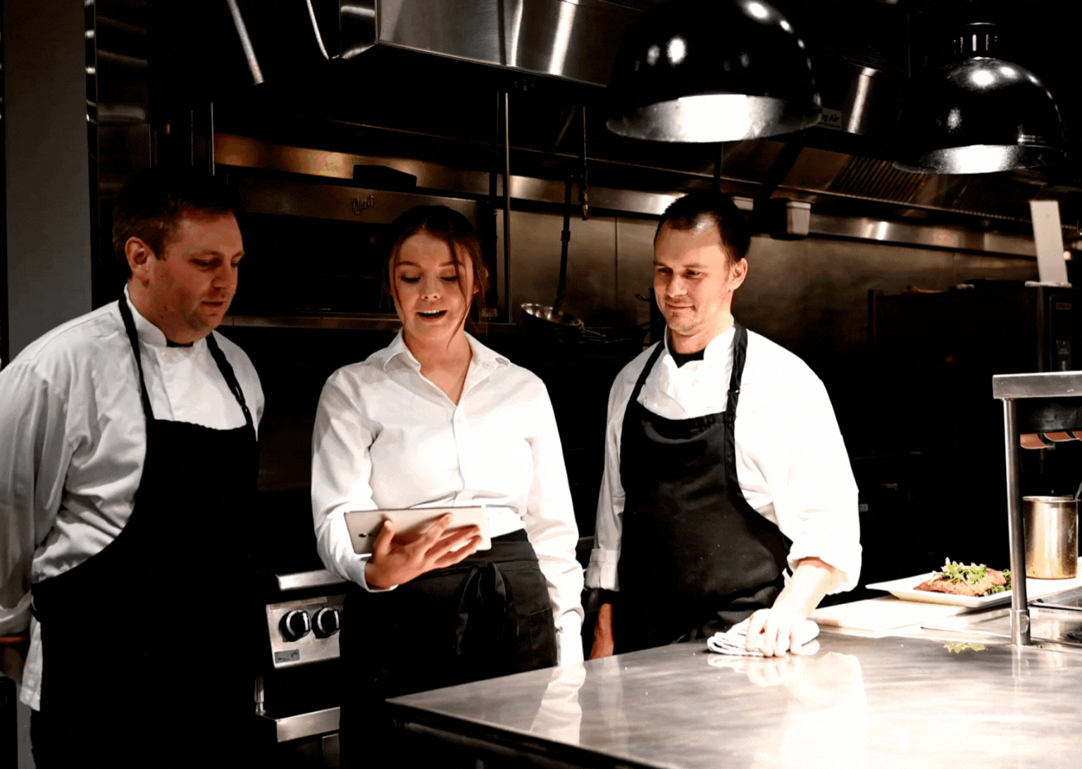Hospitality team training session with chefs collaborating in a professional kitchen, representing AW2’s expertise in food business operations and leadership development.